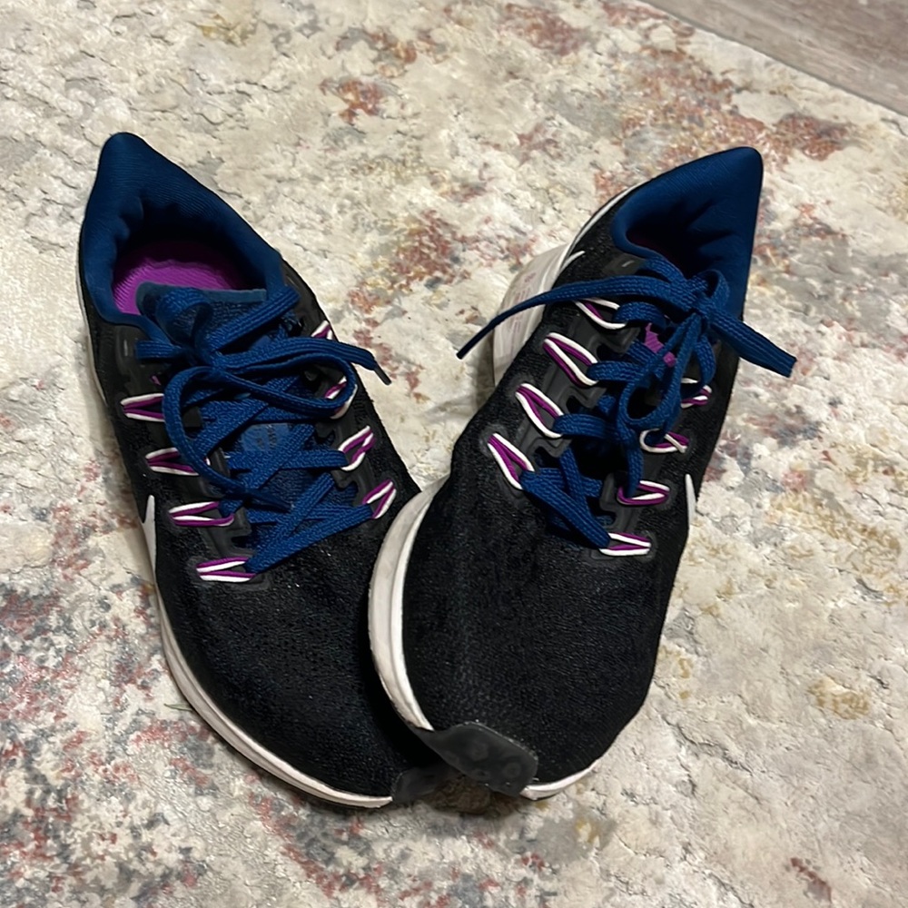 Athletic black Nike sneakers with blue laces and hints of purple throughout them